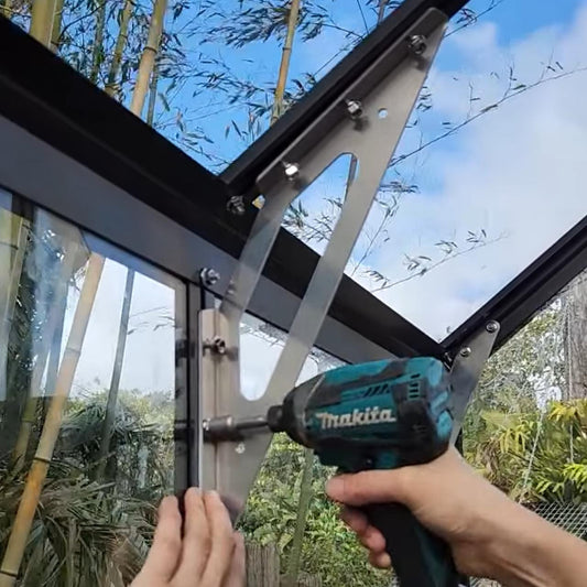 Installing a stainless steel eave brace on a black framed glass structure using a Makita power drill outdoors